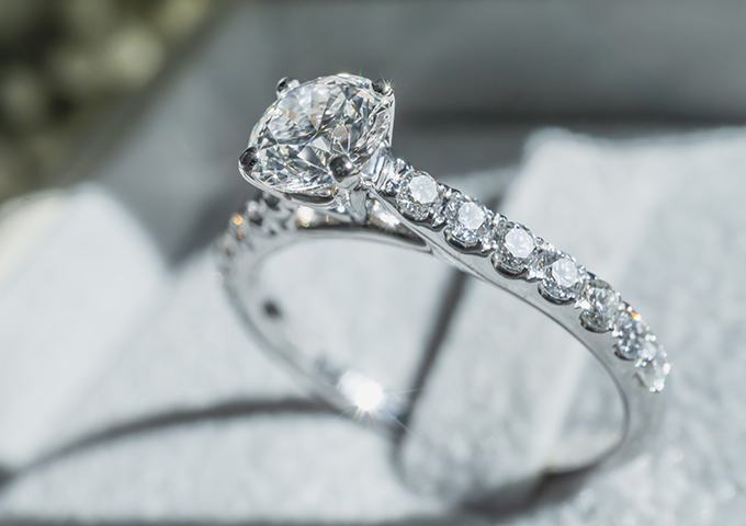 Close up of diamond ring with white flower, sunlight and shadow background. Love, valentine, relationship and wedding concept. Soft and selective focus.